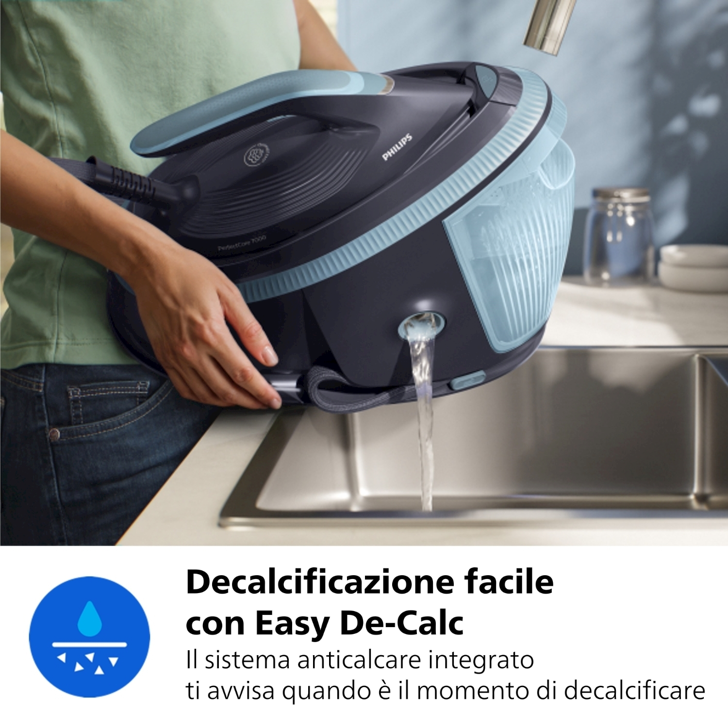Una persona tiene un ferro da stiro Philips nero e blu sopra un lavandino, esce acqua. Il testo dice 'Easy De-Calc'.
