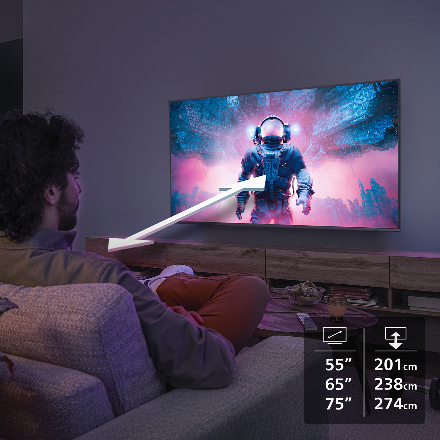 Bir adam astronot gösteren bir TV izliyor. Beyaz bir ok adamdan ekrana doğru işaret ediyor. TV boyutları listeleniyor.
