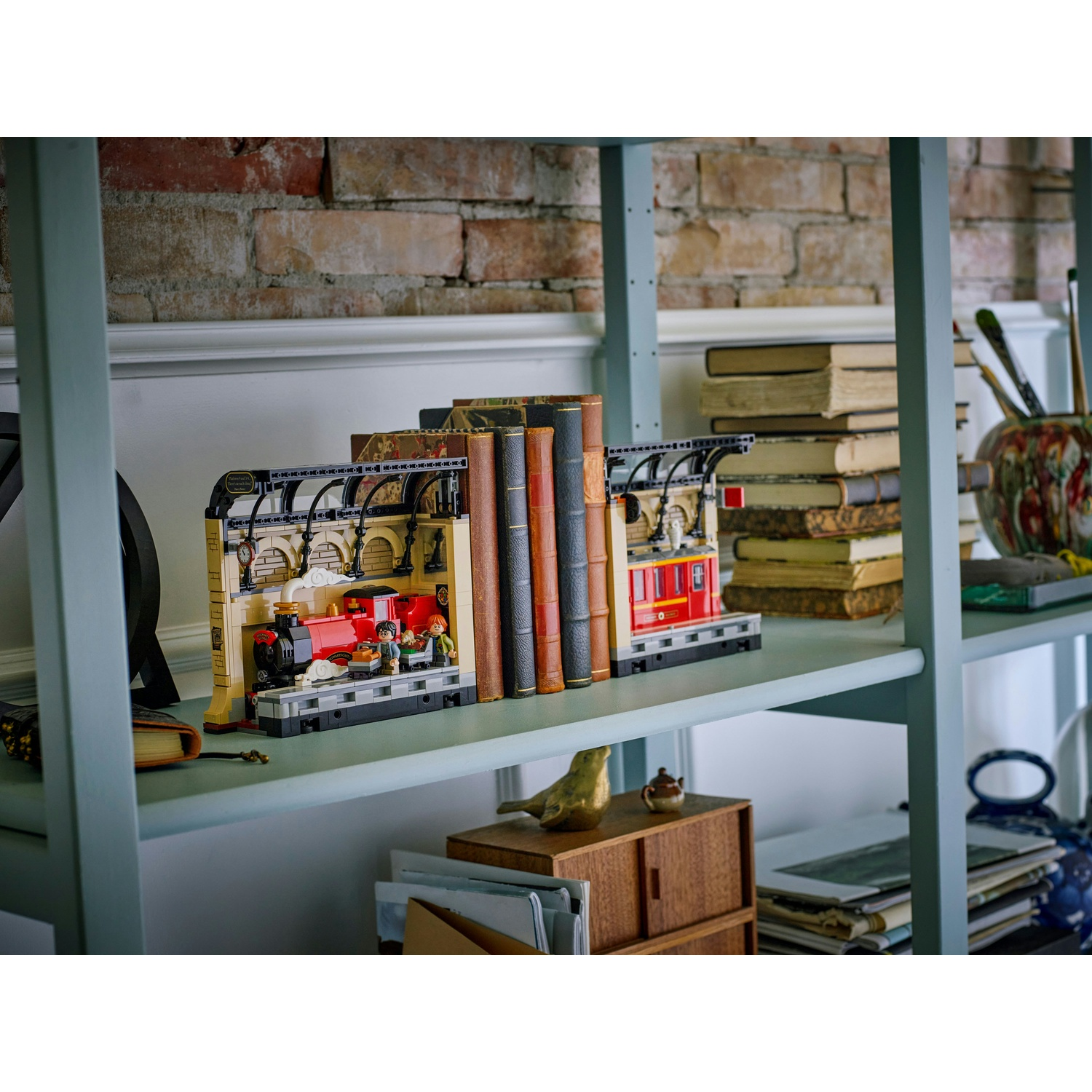 Una mensola espone un set Lego di Harry Potter, libri e forniture artistiche. Lo sfondo mostra un muro di mattoni.