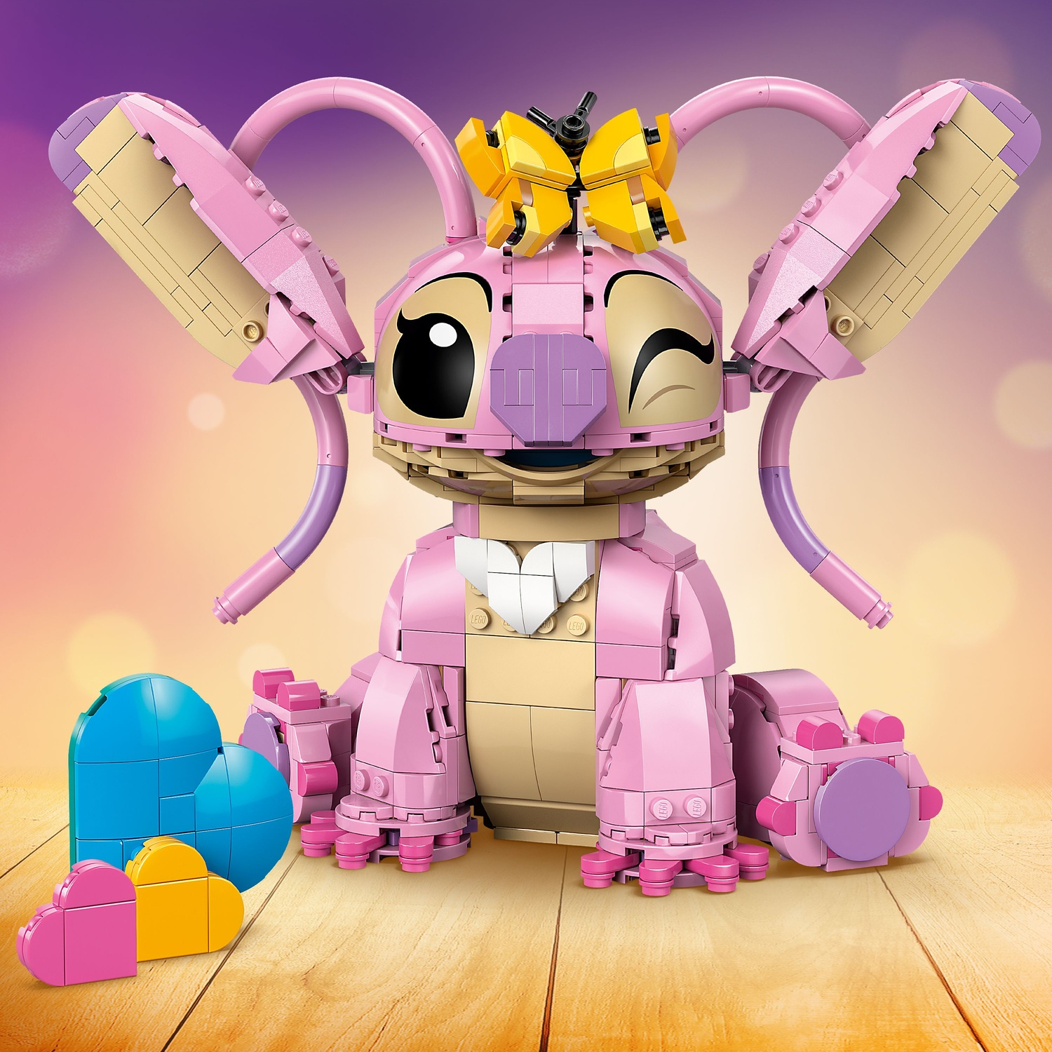 Una figura Lego di Angel di Lilo & Stitch che fa l'occhiolino. Colori rosa, beige e giallo. Tre forme di cuore in primo piano.