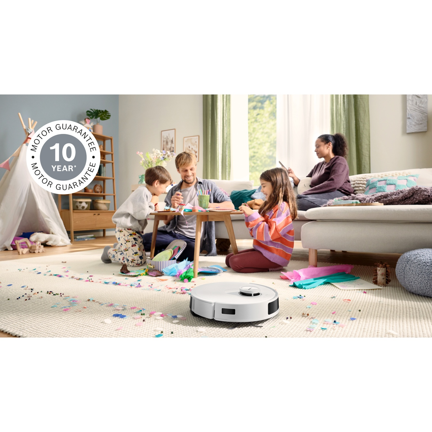 Familie knutselt met een robotstofzuiger. Kinderen en ouders knutselen op een kleed met confetti. Een vrouw gebruikt een tablet.