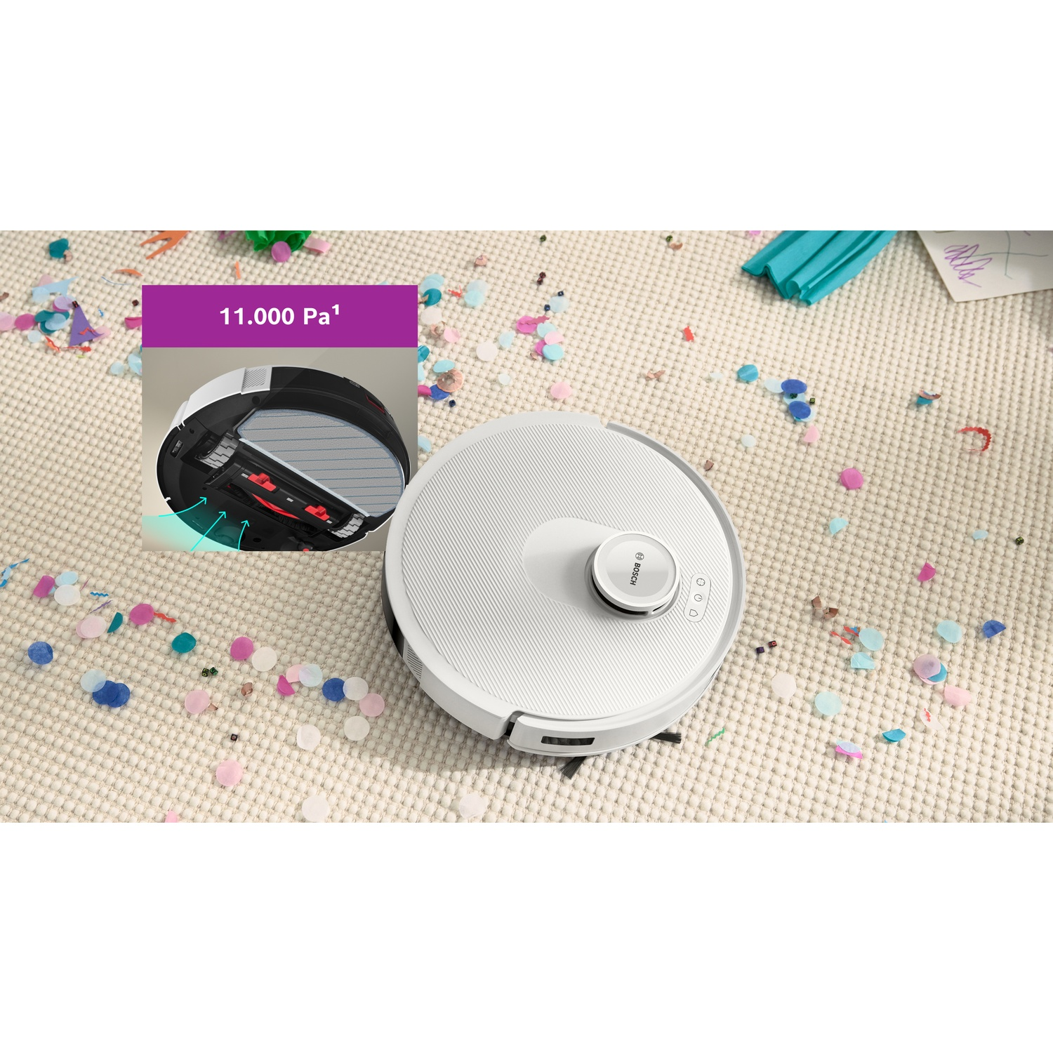 Een witte robotstofzuiger op een tapijt bedekt met confetti. Een inzet toont de onderkant van de stofzuiger met een luchtinlaat.
