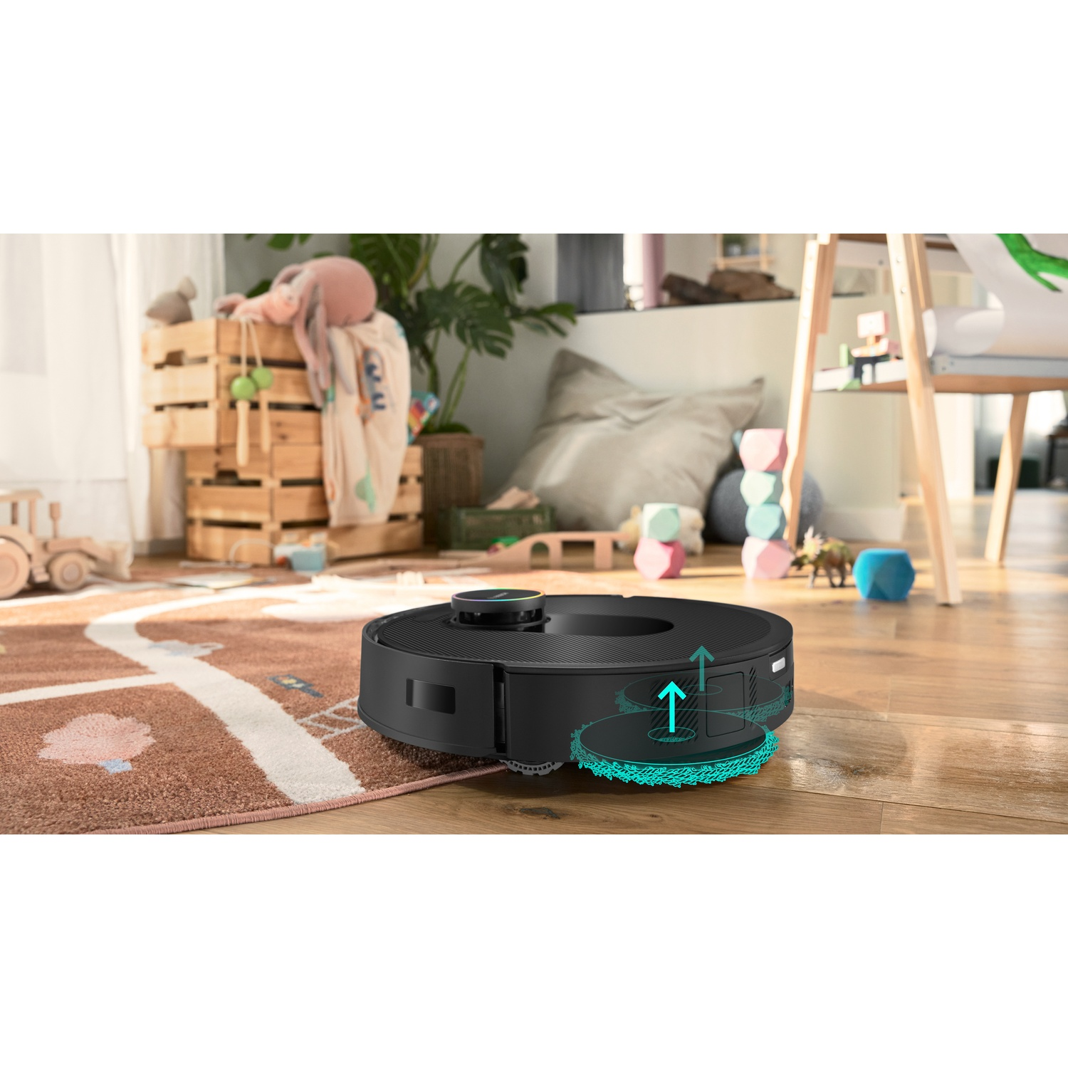 Een zwarte robotstofzuiger op een houten vloer, met een tapijt en speelgoed op de achtergrond. Pijlen tonen het reinigingsproces.