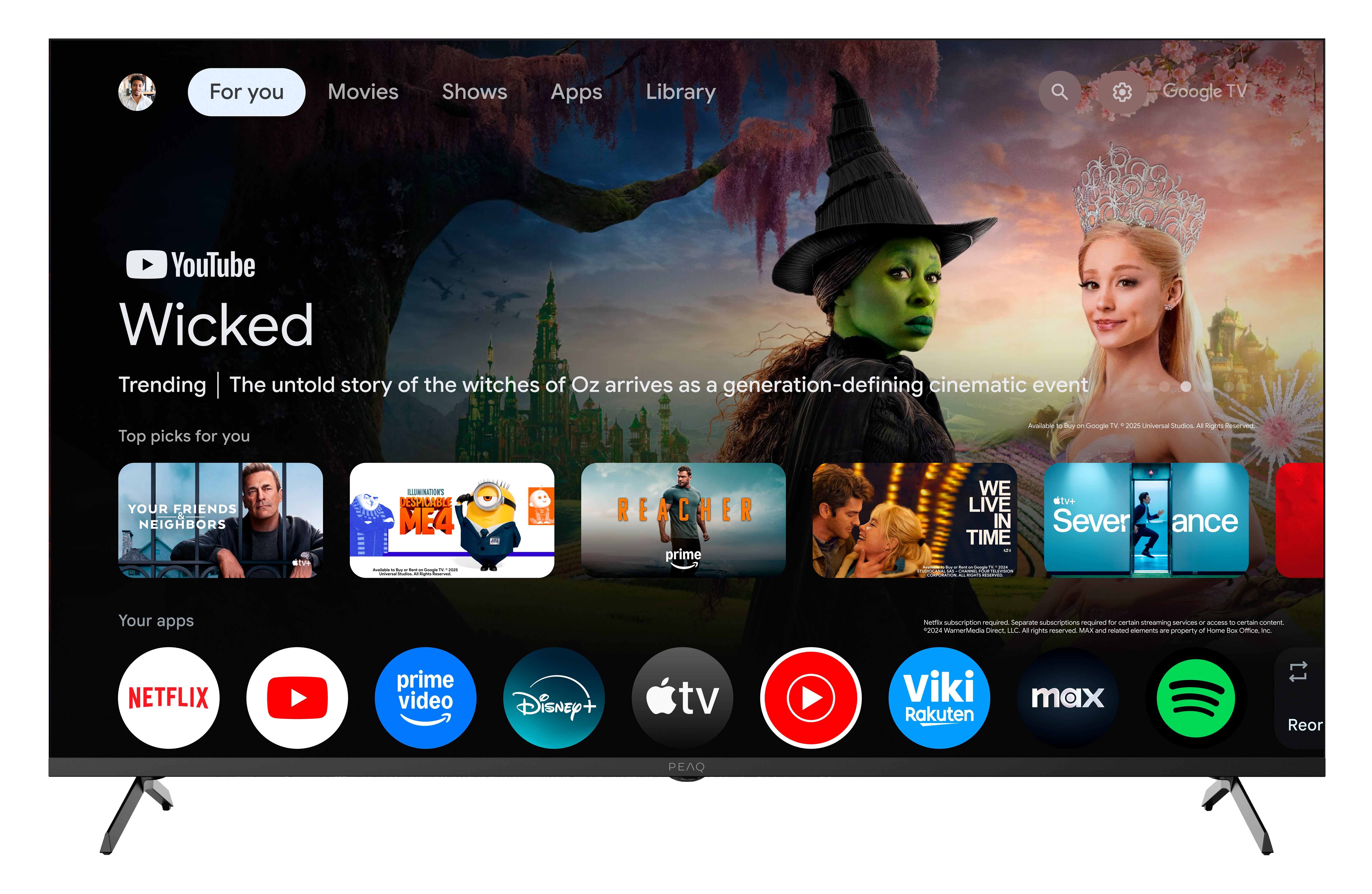 Ekran telewizora wyświetla 'Wicked' na YouTube, ze zdjęciami wiedźmy i kobiety. Ikony aplikacji, takie jak Netflix, YouTube i Spotify, znajdują się na dole.