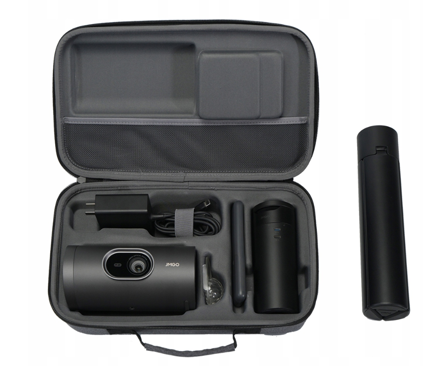 Otwarta szara walizka z czarnym projektorem, ładowarką i akcesoriami. Z boku osobna czarna tuba.