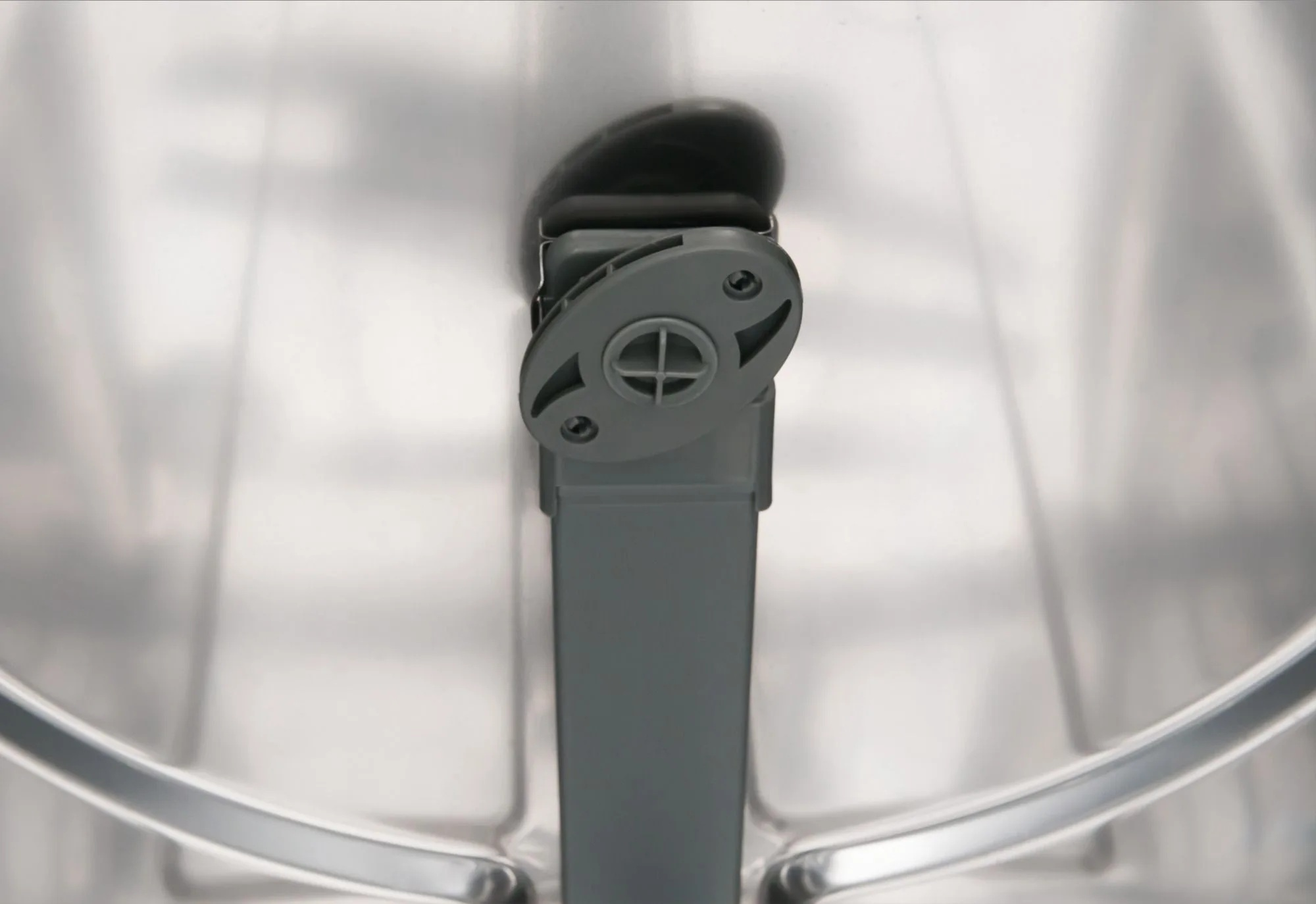 Widok wewnątrz zmywarki. Widoczny szary plastikowy element z okrągłą górą i prostokątnym korpusem.