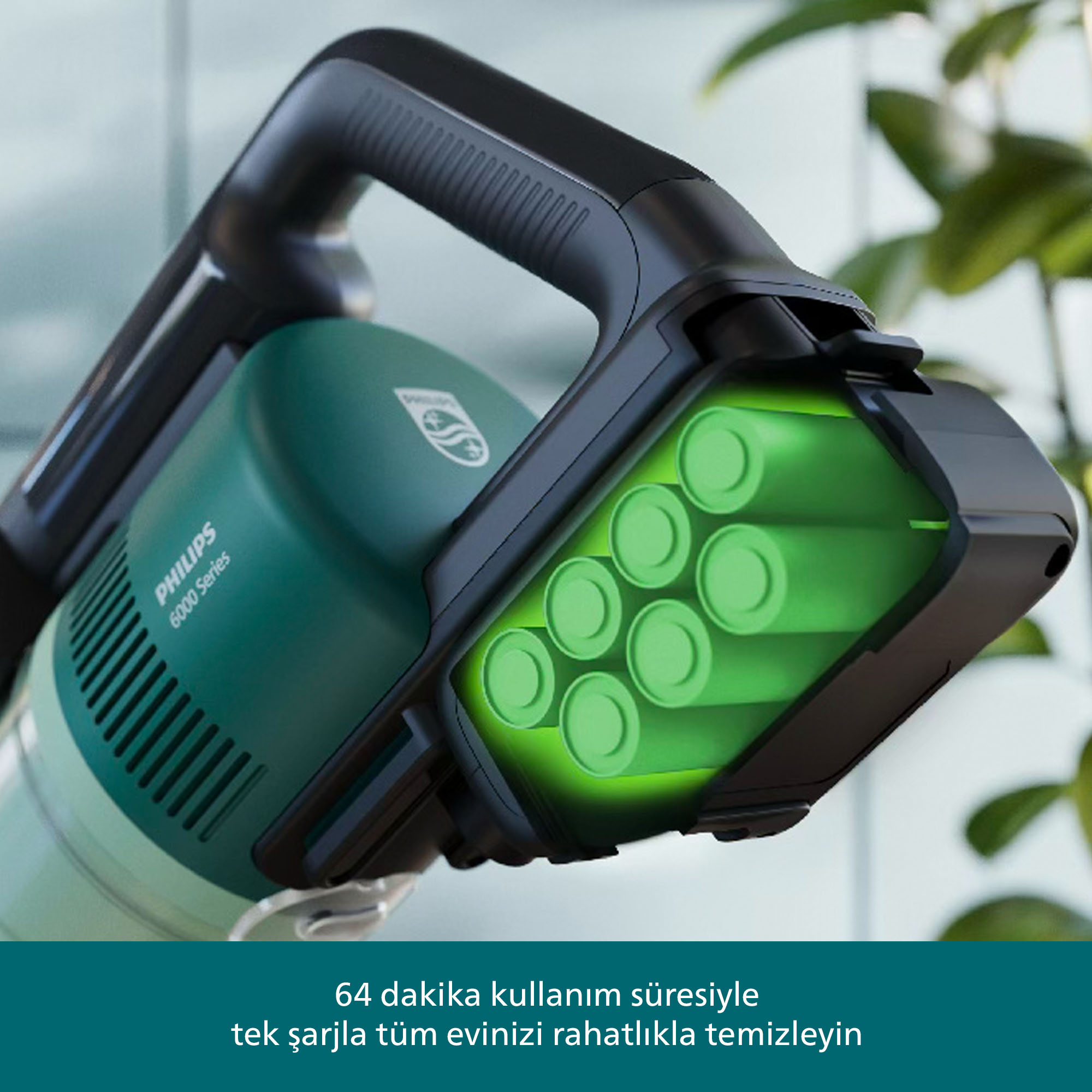 Pilli yeşil Philips elektrikli süpürgesi. Siyah tutma kolu. Yeşil parlayan piller. Arka plan bulanık yapraklar ve duvar.