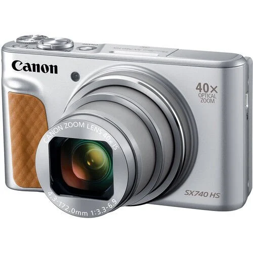 Kahverengi bir tutamağa sahip gümüş renkli bir Canon dijital fotoğraf makinesi. Yakınlaştırma detayları ve model bilgileri bulunan büyük bir lense sahip.