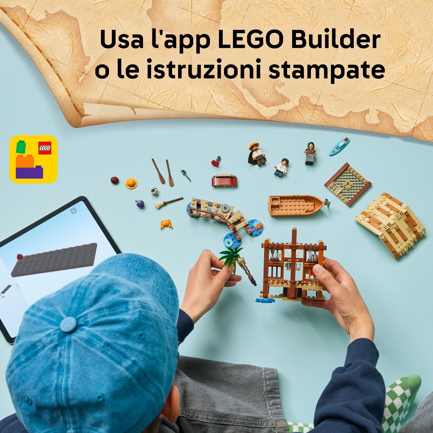 Un bambino costruisce un set LEGO, usando un tablet e istruzioni. Pezzi LEGO sparsi su una superficie blu, una mappa sullo sfondo.