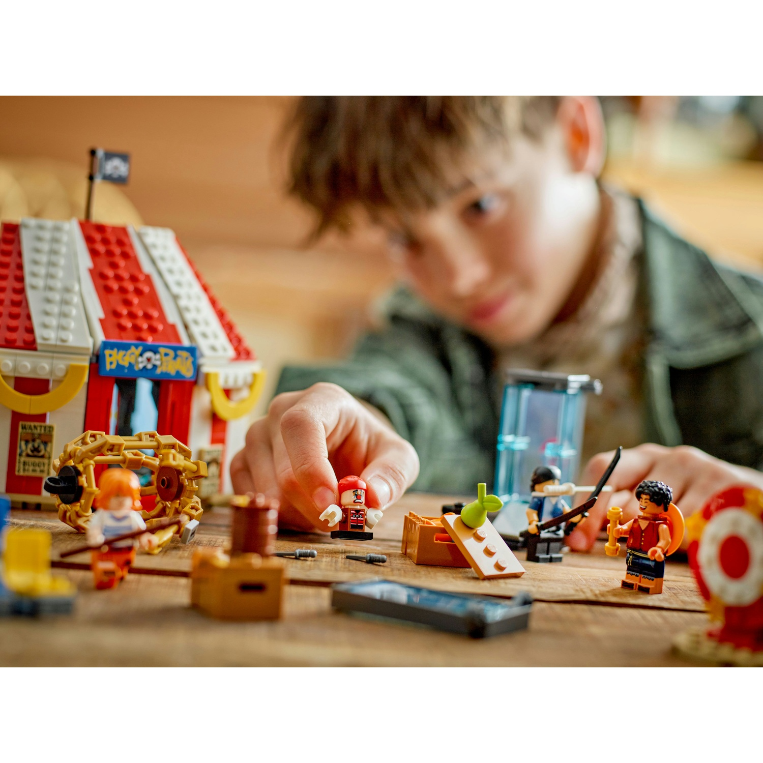 Un ragazzo che gioca con un set Lego del circo. Il set include una tenda, personaggi, un carro e altri oggetti di scena del circo.