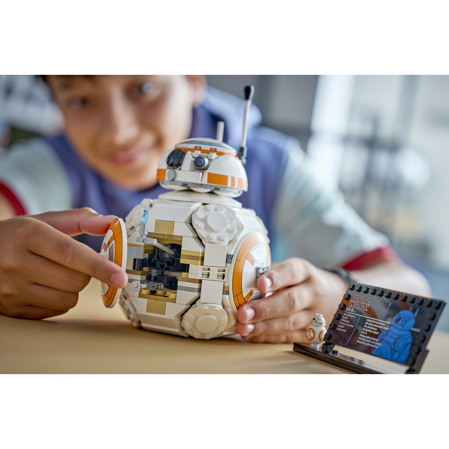 Un ragazzo indica un droide Lego BB-8. Il droide è bianco e arancione. Sono presenti anche un piccolo Lego BB-8 e una scheda informativa.