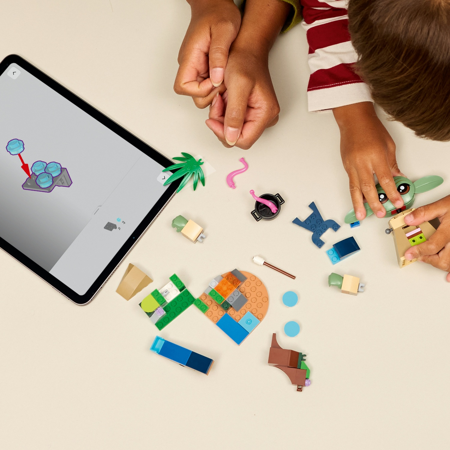 Mani che assemblano un set Lego Star Wars. Il tablet mostra le istruzioni. Pezzi Lego sparsi includono Baby Yoda, palma e vari mattoncini.