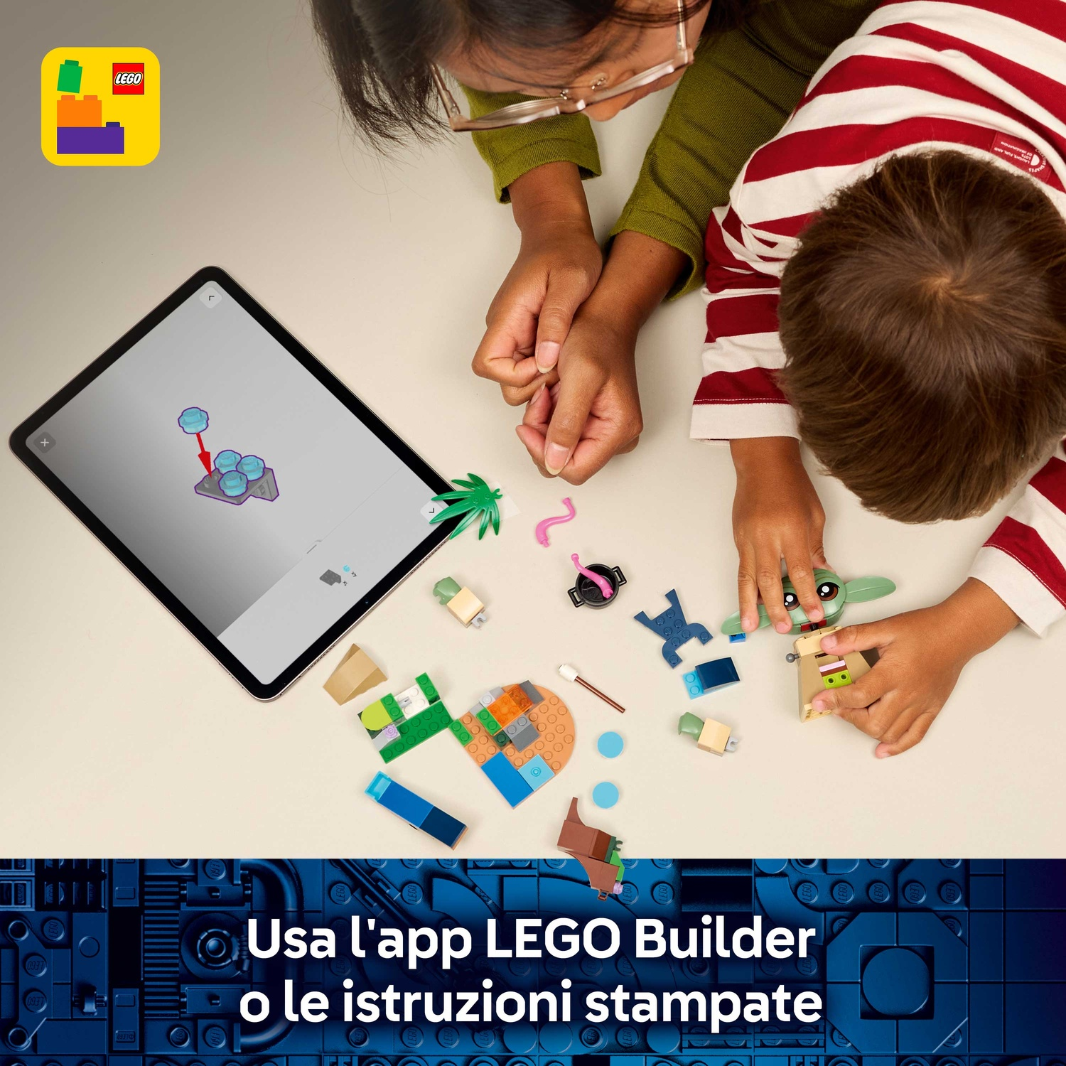 Un bambino e un adulto costruiscono con i mattoncini Lego. Un tablet mostra le istruzioni. Vari pezzi Lego sono sparsi.