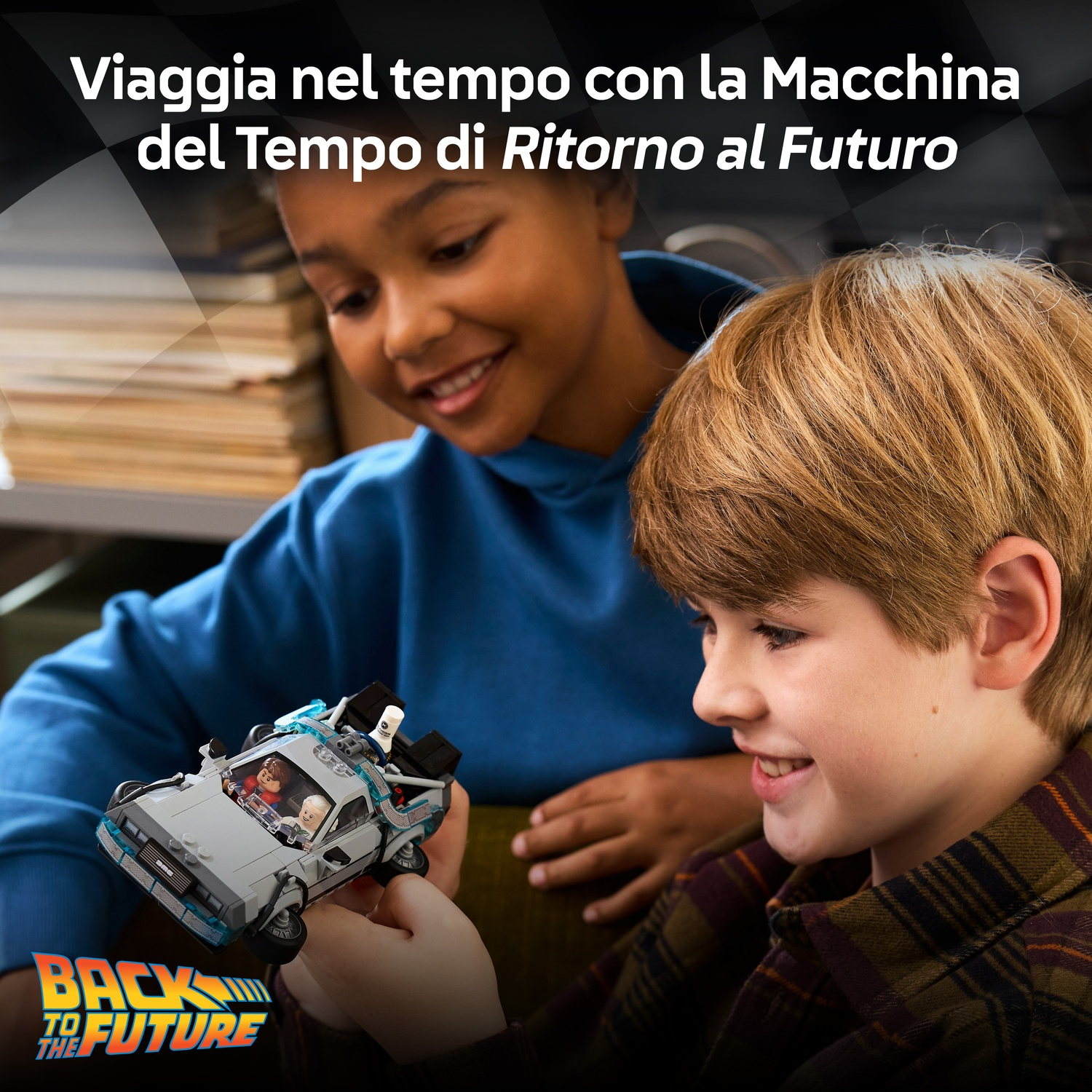 Due ragazzi guardano un'auto giocattolo di Ritorno al Futuro. L'auto è tenuta da un ragazzo, l'altro sorride.