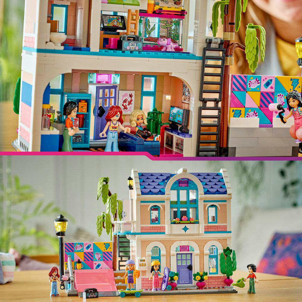Ein Lego-Haus mit mehreren Etagen wird gezeigt, einschließlich Miniaturfiguren, Möbeln und dekorativen Elementen. Das Haus steht auf einem Holztisch.