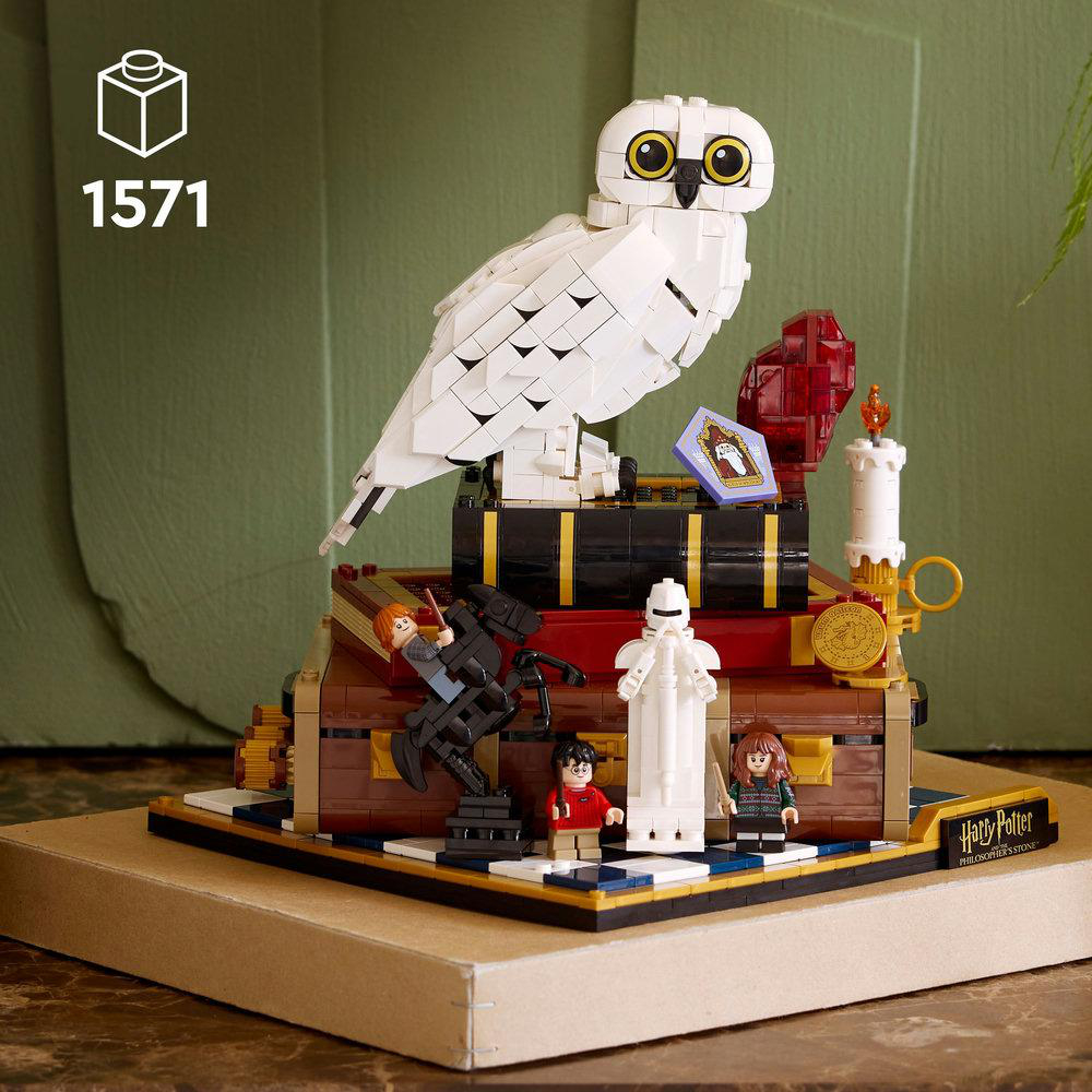 Lego Harry Potter Set. Ein großer weißer Eule sitzt auf Büchern. Miniaturfiguren sind Harry, Hermine und Ron. Eine Kerze und eine Truhe sind ebenfalls sichtbar.