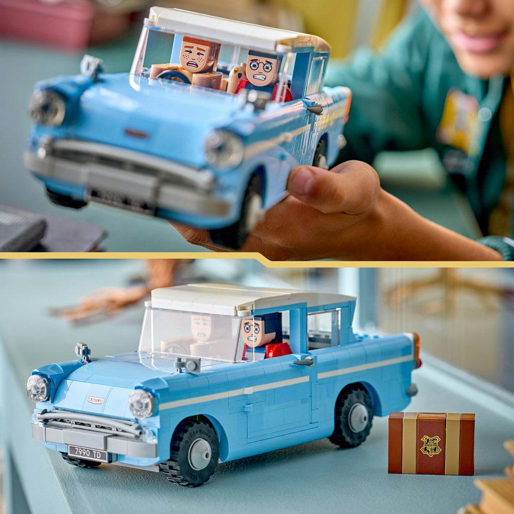 Ein blaues Lego-Auto mit zwei Minifiguren im Inneren, das von Händen gehalten wird. Das Auto hat schwarze Reifen, ein weißes Dach und ein Nummernschild.