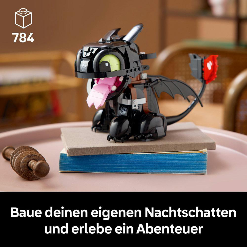 Ein Lego Nachtschatten Drachenmodell auf einem Bücherstapel. Der Drache ist schwarz mit rosa Zunge und grünen Augen. Die Zahl 784 ist sichtbar.