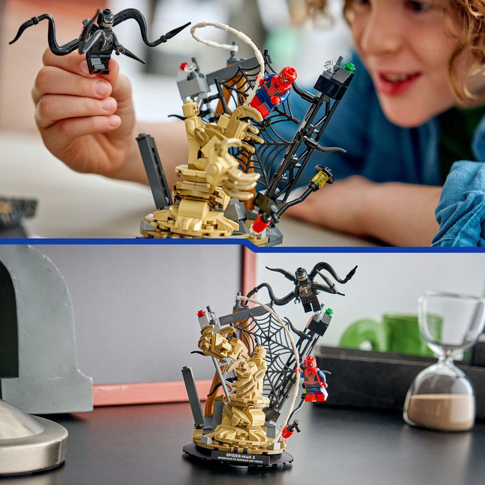 Ein Kind hält eine Venom-Figur in der Nähe eines Lego-Sets mit Spider-Man, Sandman und einer Netzstruktur.