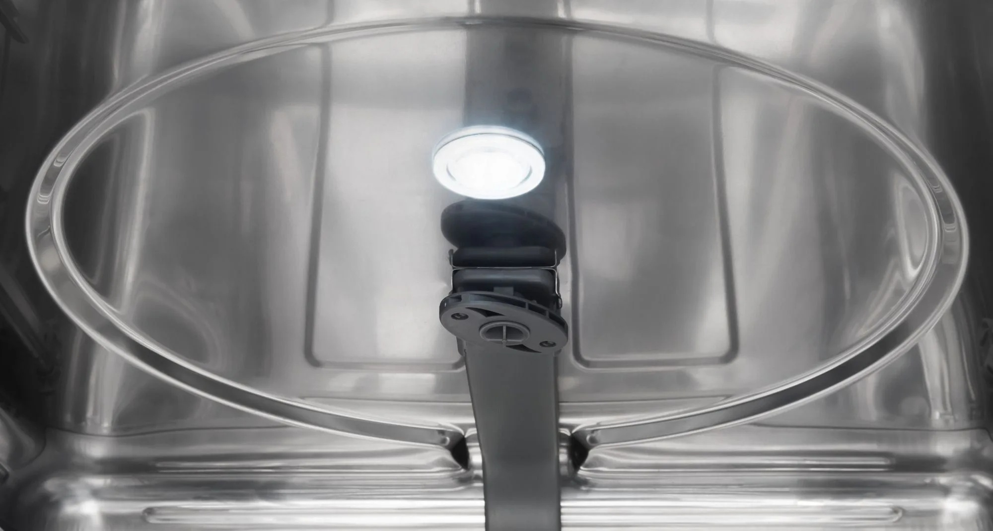 Wewnątrz zmywarki widoczne jest przezroczyste plastikowe ramię spryskiwacza i jasne światło. Wnętrze jest ze stali nierdzewnej.