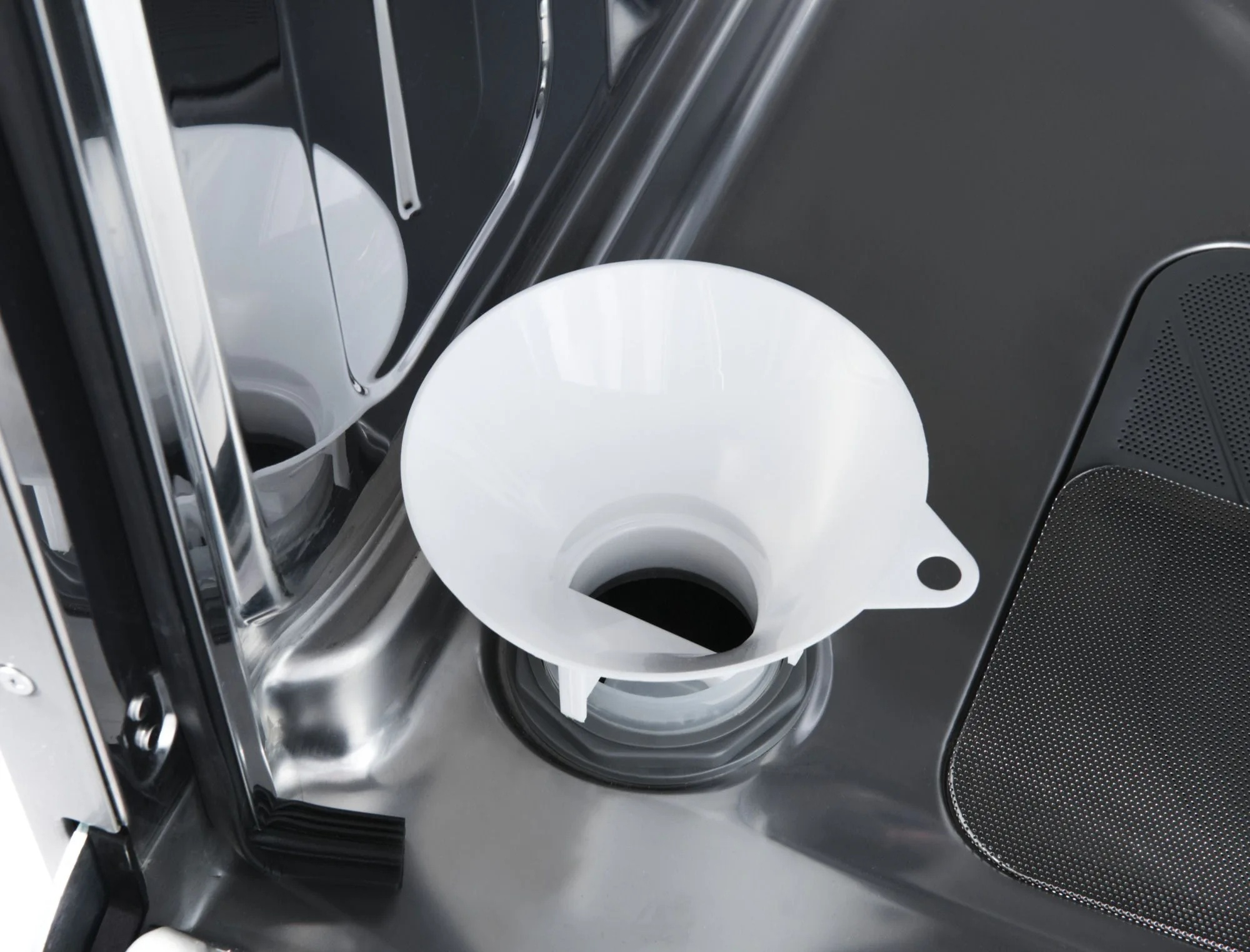 Biały lejek umieszczony w zmywarce. Wnętrze zmywarki jest czarne i srebrne.