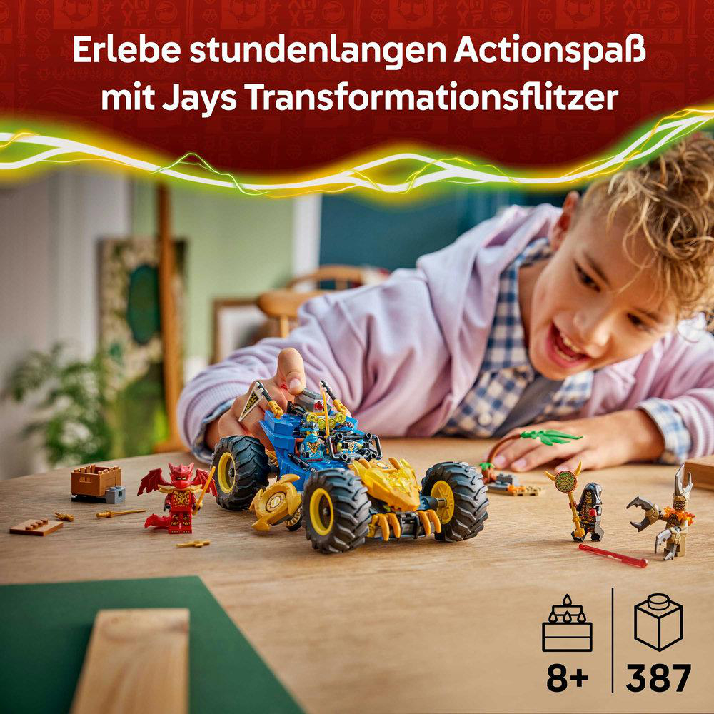Ein Junge lächelt und spielt mit einem Spielzeugauto. Anderes Spielzeug und eine LEGO-Box liegen auf dem Tisch. Text: 8+, 387.