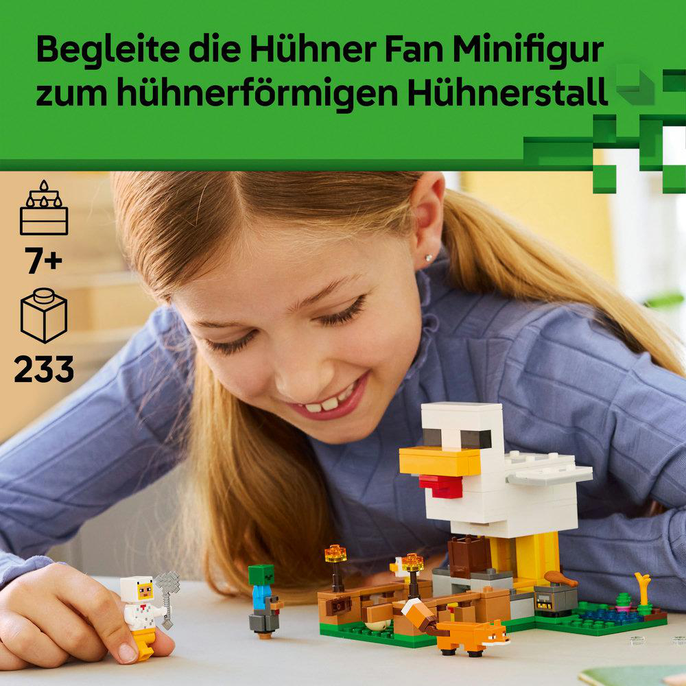 Ein Mädchen lächelt ein Hühnerstallmodell an. Das Modell zeigt eine große weiße Hühnerstruktur mit kleinen Lego-Figuren und einem Fuchs.