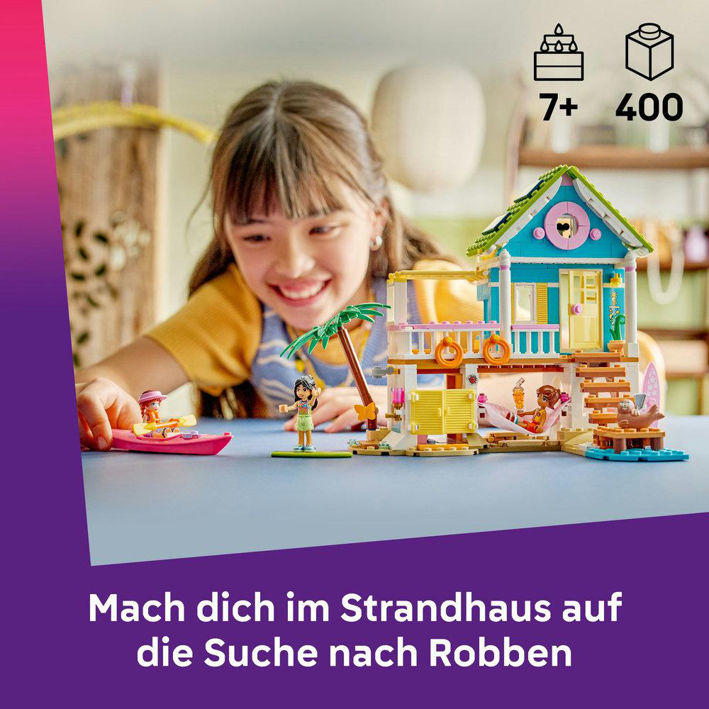 Ein Mädchen lächelt ein Lego-Strandhaus mit Figuren an, dazu ein Kajak und eine Palme. Text: 'Mach dich im Strandhaus auf die Suche nach Robben'.