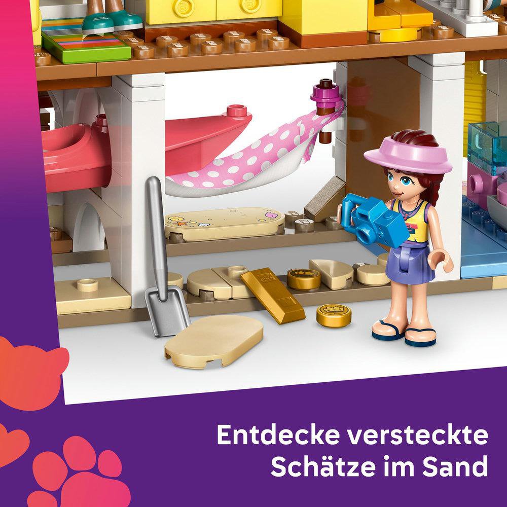 Eine Lego-Szene mit einer Mädchenfigur, einer Schaufel und Goldbarren. Der Hintergrund zeigt eine Hausstruktur und Text.