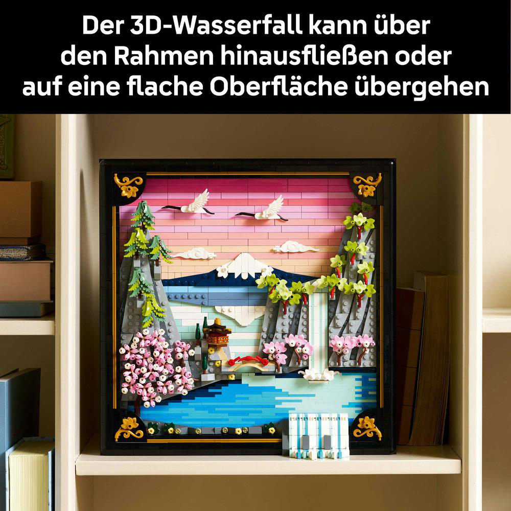 Ein gerahmtes 3D-Lego-Diorama einer Wasserfallszene mit Bergen, Bäumen, Wasser und Vögeln. Es steht auf einem Regal.
