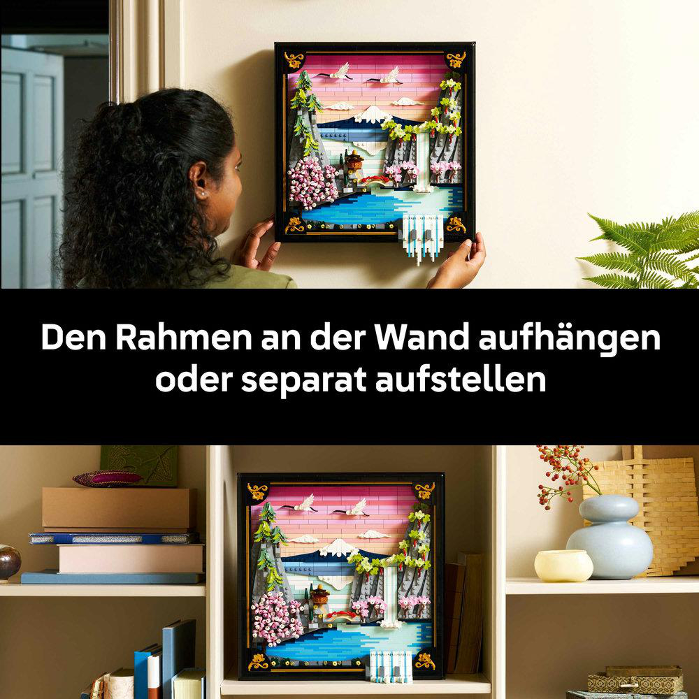 Eine Frau hängt ein gerahmtes Kunstwerk mit einer japanischen Landschaft auf. Der Rahmen ist schwarz. Das Kunstwerk zeigt Wasserfall und Berge.