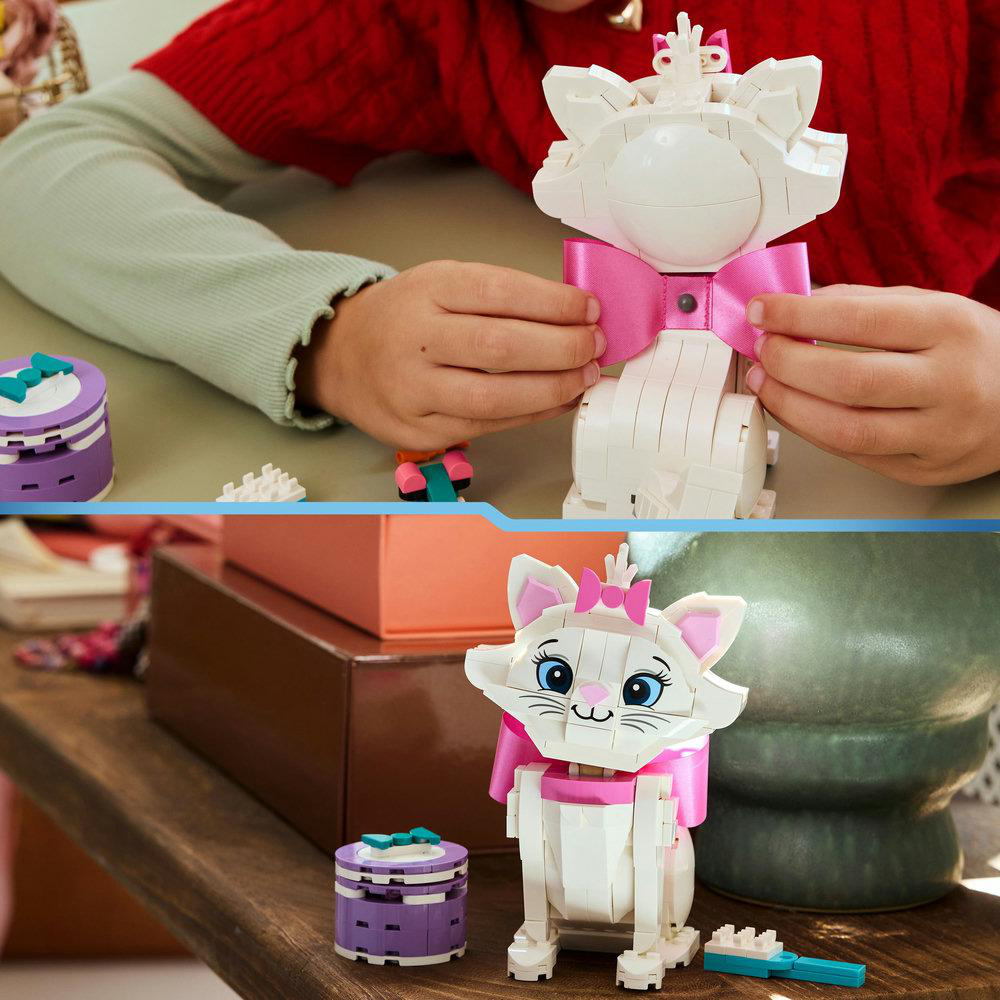 Eine Person hält eine weiße Lego-Katze mit einer rosa Schleife. Lego-Katze hat blaue Augen, eine rosa Schleife auf dem Kopf und eine rosa Schleife am Hals.