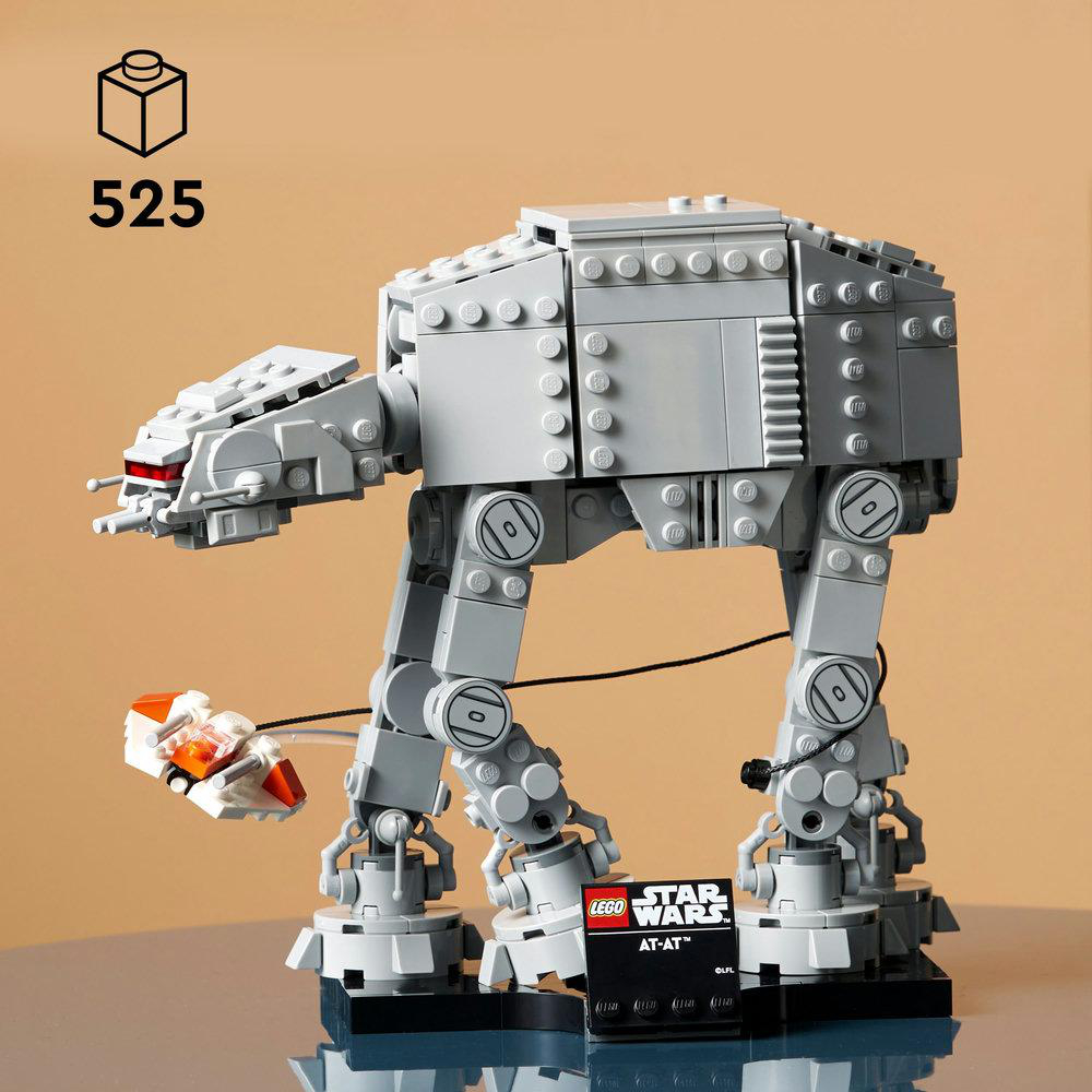 Ein Lego Star Wars AT-AT-Modell steht auf einer schwarzen Basis. Ein kleines weißes und oranges Raumschiff ist damit verbunden. Der Hintergrund ist beige.
