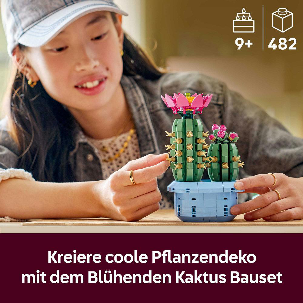 Eine junge Person baut ein Lego-Kaktus-Set. Das Set enthält zwei Kakteen, rosa Blüten und einen blauen Topf. Der Hintergrund ist unscharf.