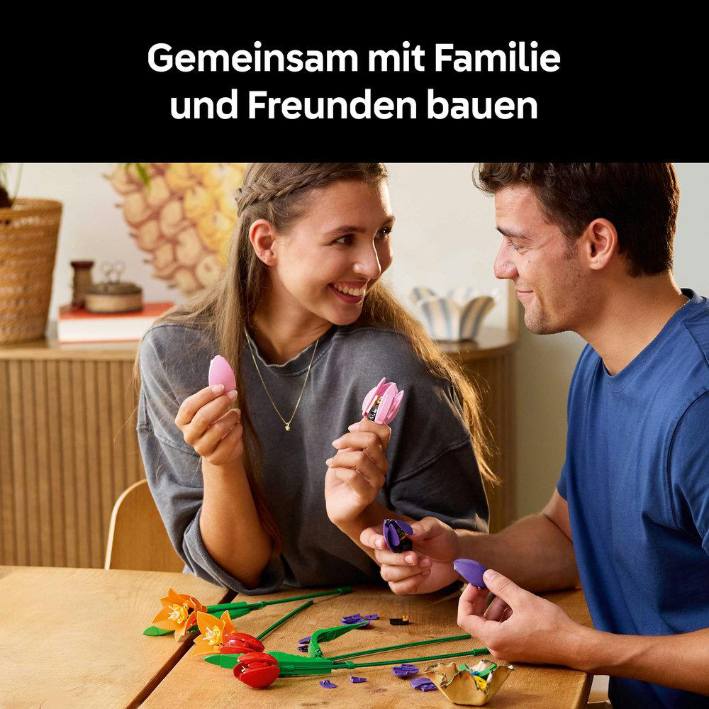 Ein Mann und eine Frau bauen ein buntes Tulpen-Set. Sie lächeln. Im Vordergrund befinden sich Tulpenkomponenten.