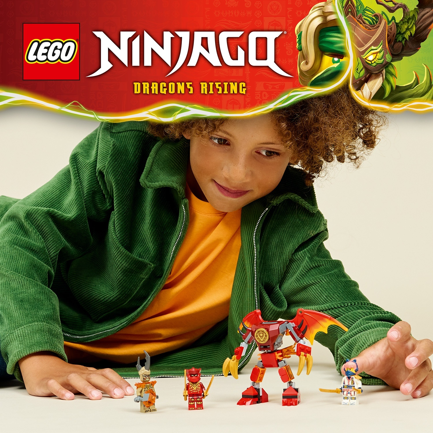 Un ragazzo con i giocattoli LEGO Ninjago. Robot rosso, personaggi e logo. Giacca verde, camicia arancione. Sfondo: design rosso e verde.