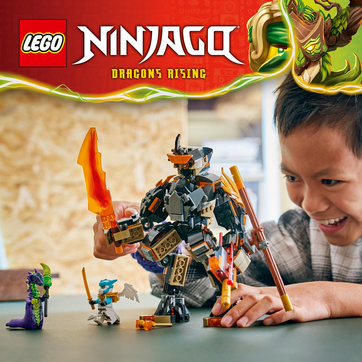 Un ragazzo sorride, giocando con il set Lego Ninjago. Una grande figura di robot è di fronte ad altre figure Lego. Lo sfondo ha un logo Ninjago.