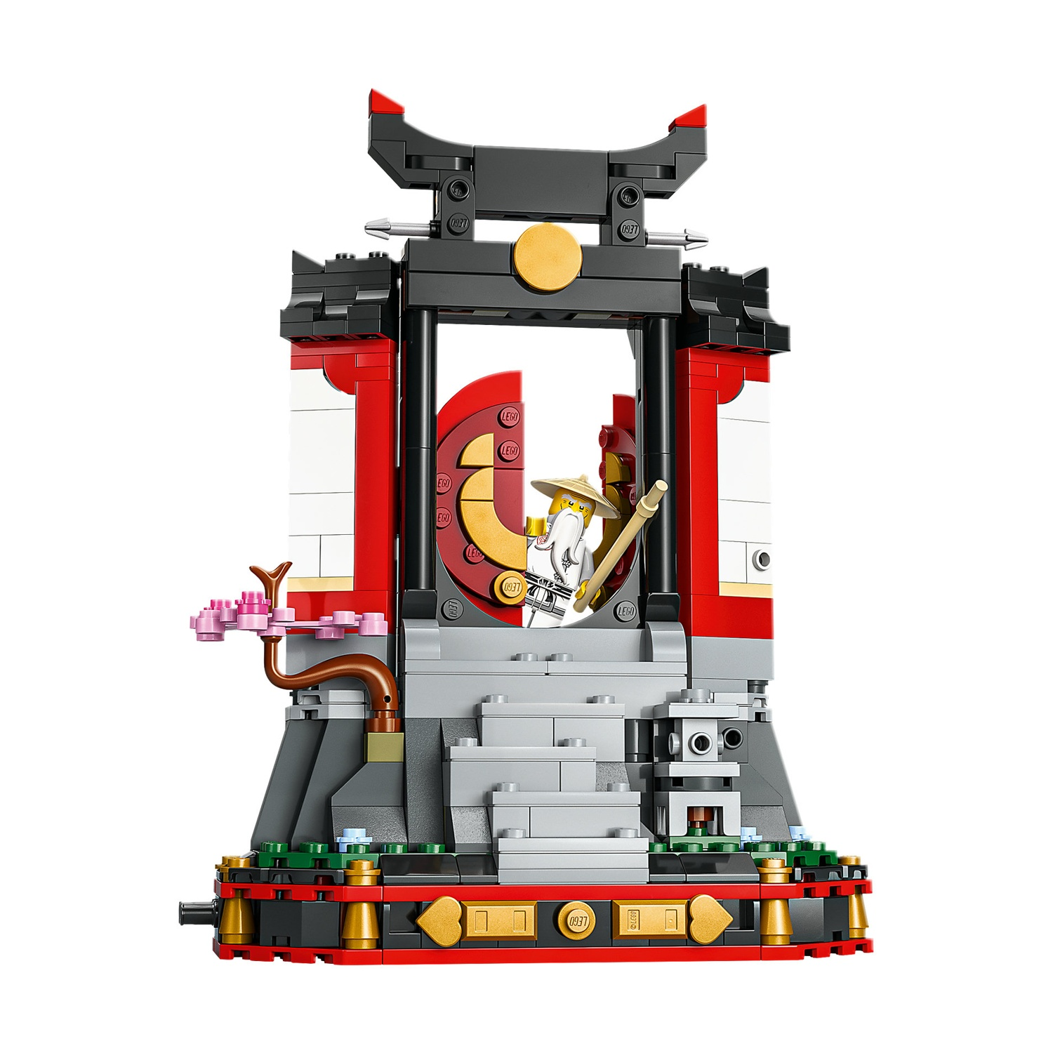 Un set del tempio Lego con una figura che tiene un bastone. Il tempio è rosso, nero e bianco, con un albero di ciliegio accanto.