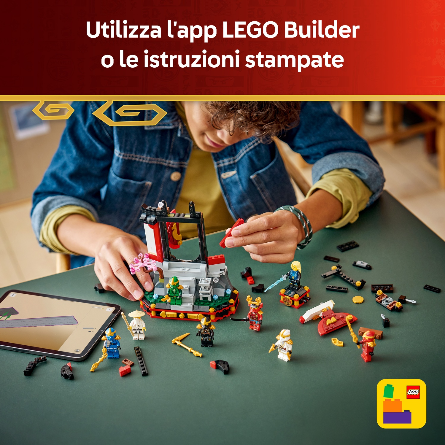 Un bambino costruisce un set Lego con personaggi e un tempio su un tavolo verde. Un tablet mostra le istruzioni.