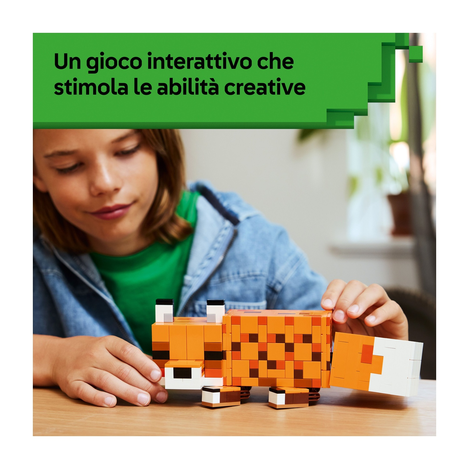 Un bambino gioca con una volpe Lego arancione su un tavolo di legno. La volpe è fatta di blocchi. Il testo sopra recita: Un gioco interattivo.