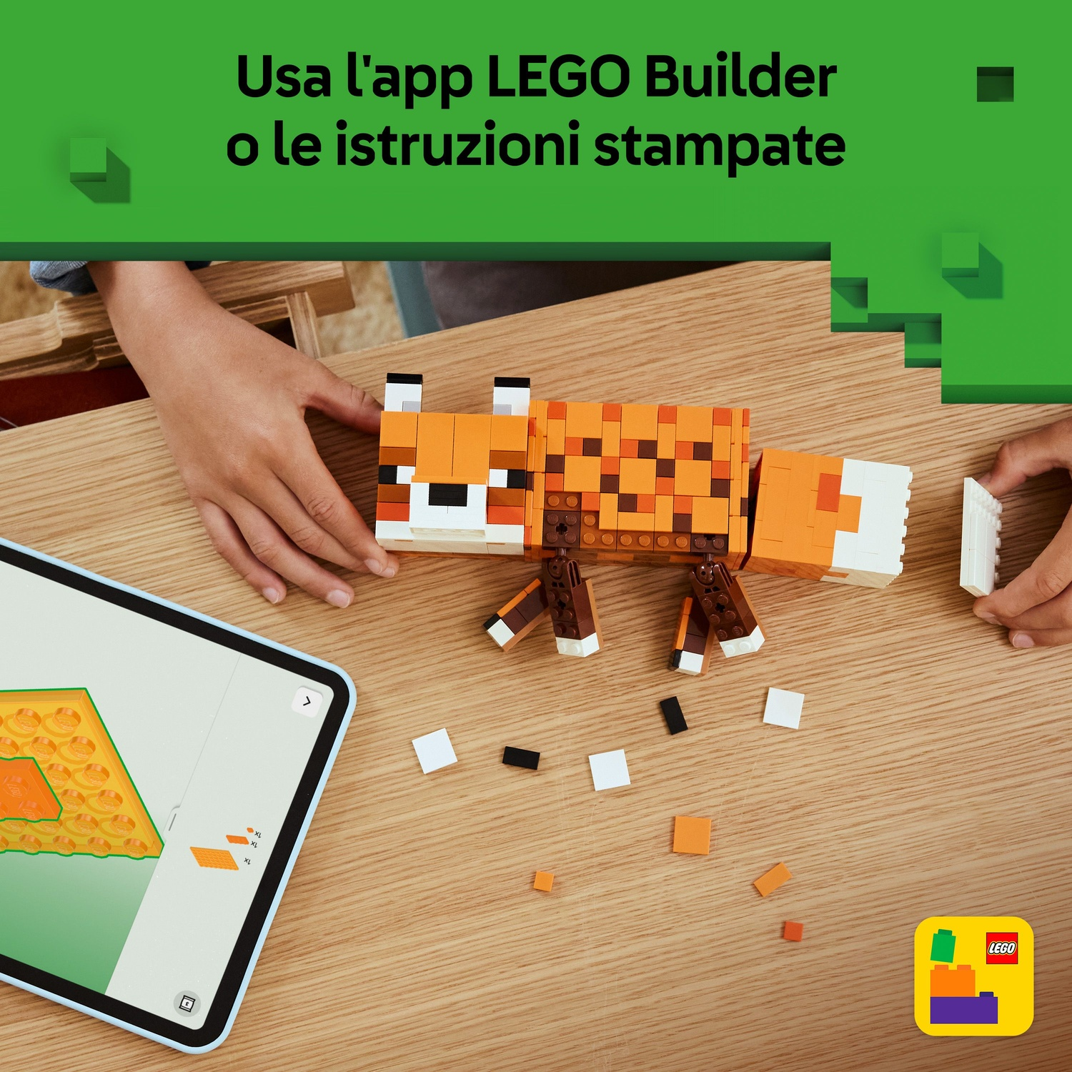 Una volpe Lego è assemblata su un tavolo di legno. Un tablet mostra le istruzioni. Le mani stanno costruendo. Mattoncini sparsi e logo Lego visibili.