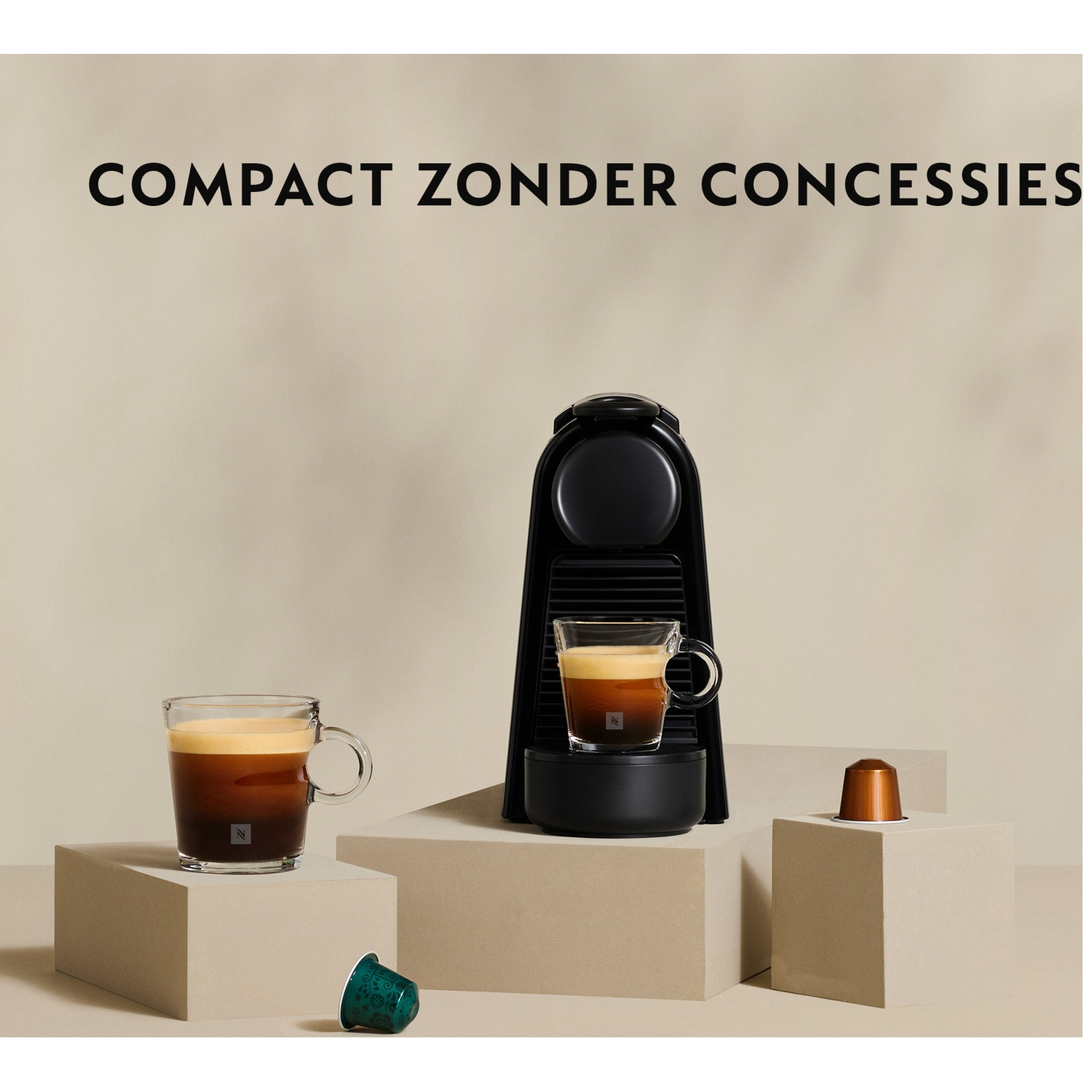 Black coffee machine with two cups of coffee. Two pods and two coffee cups are on beige blocks.