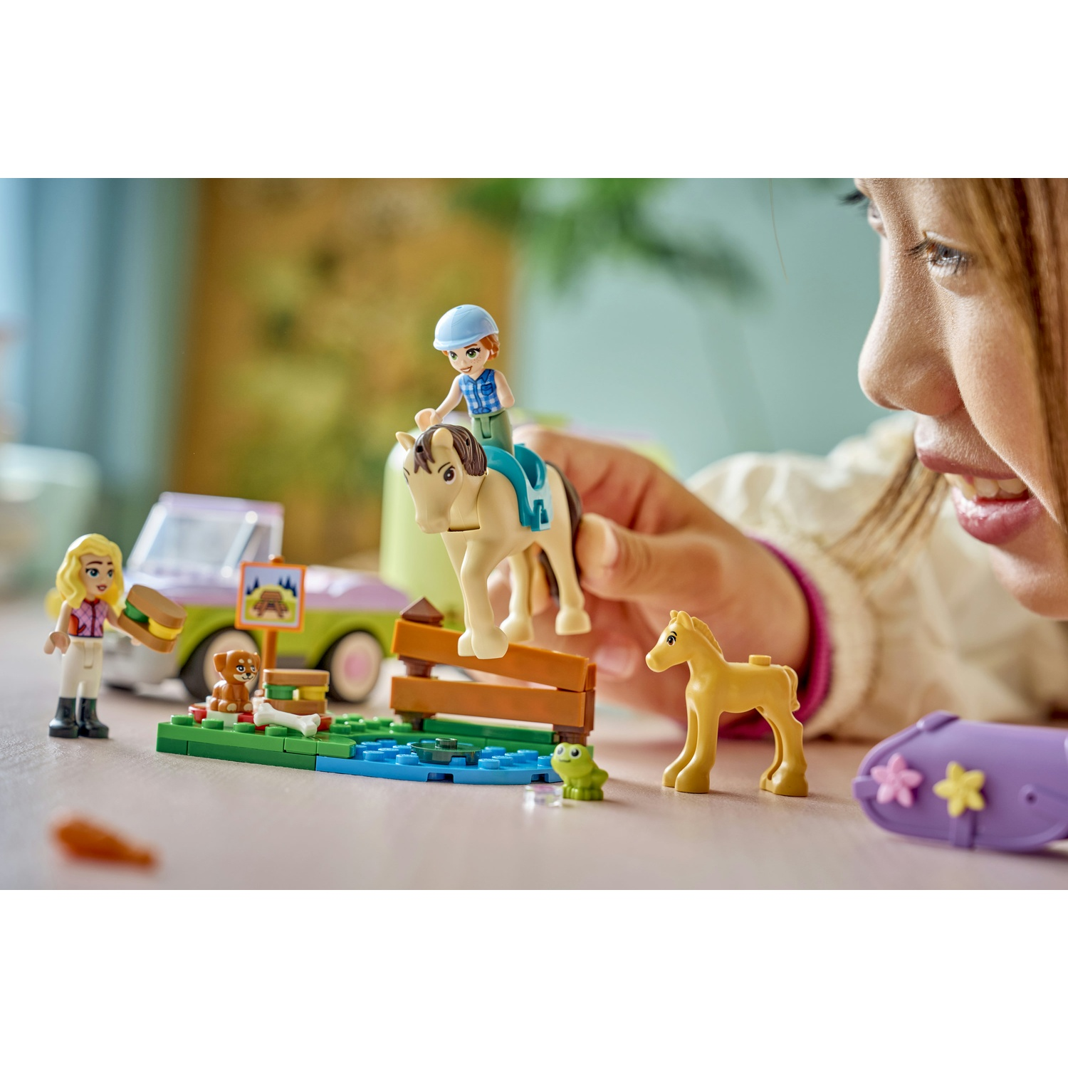 Una ragazza gioca con un set Lego Friends. Include cavallo, puledro, cavaliere, cane, auto e altri accessori.