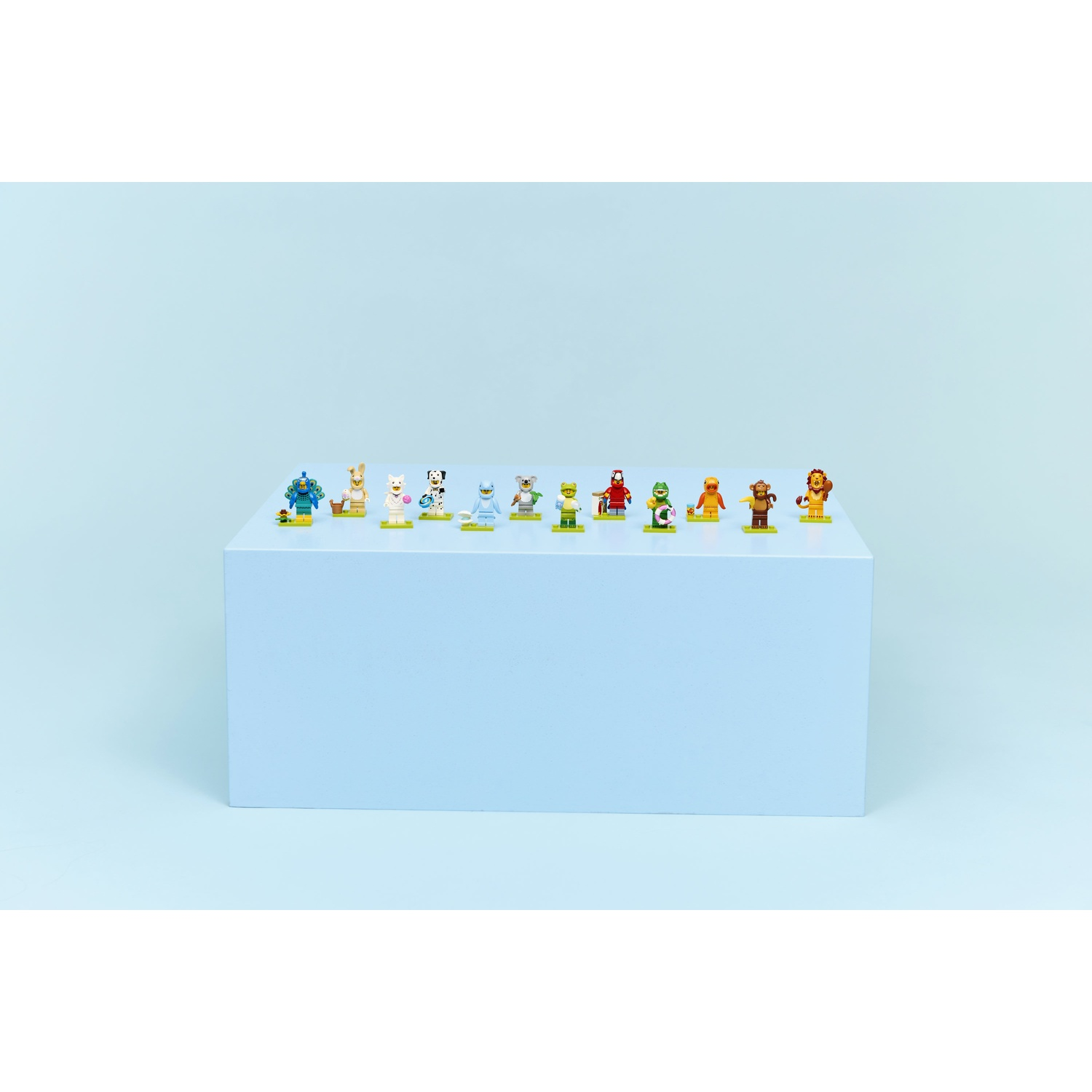 Una collezione di piccole statuette di animali, disposte su un blocco blu contro uno sfondo azzurro.