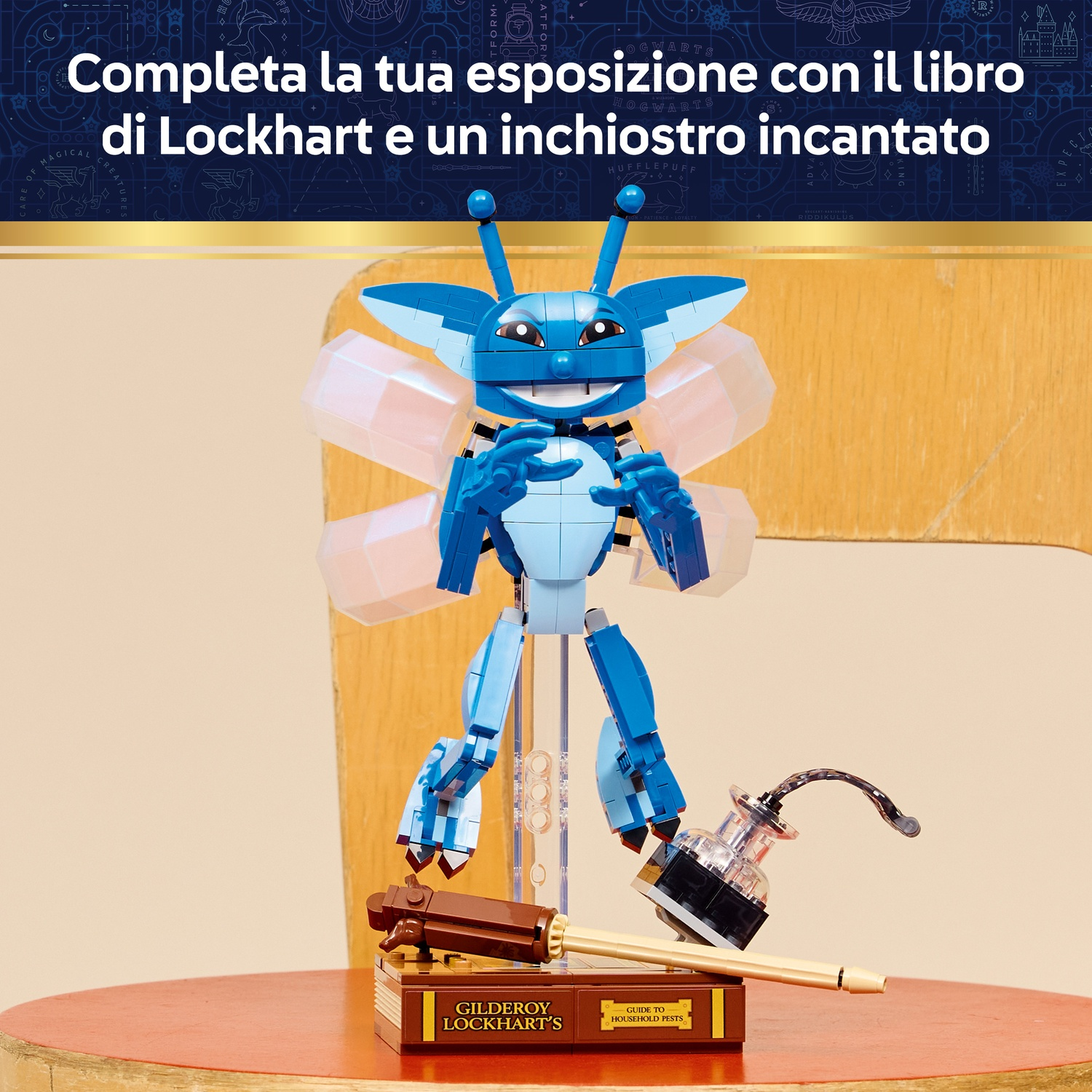 Una creatura Lego blu su un tavolo rosso. Sono presenti anche un libro, una penna e un calamaio. Lo sfondo è sfocato.