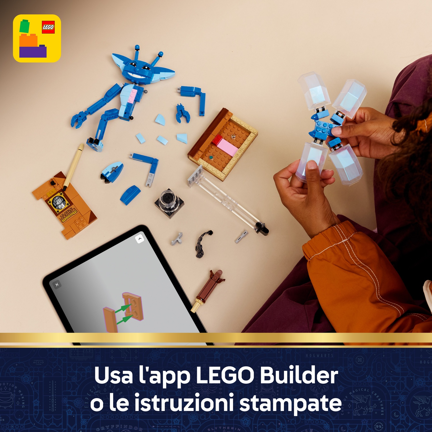Un bambino assembla una creatura Lego blu. I pezzi sono sparsi, con un tablet che mostra le istruzioni. Il logo Lego è visibile.
