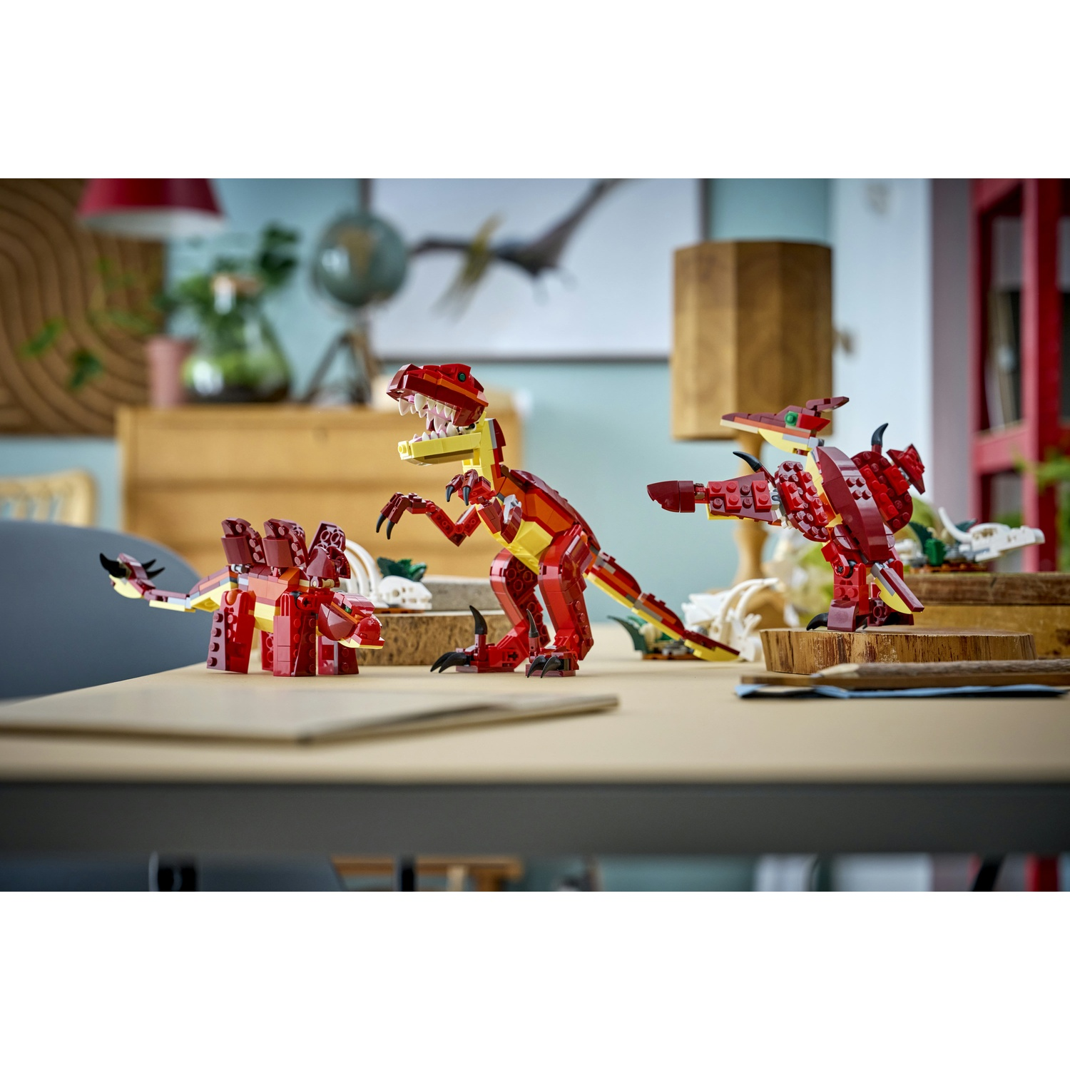 Tre dinosauri Lego su un tavolo. Uno è rosso e giallo con denti affilati. Altri sono rossi e hanno la schiena a spillo. Lo sfondo è sfocato.