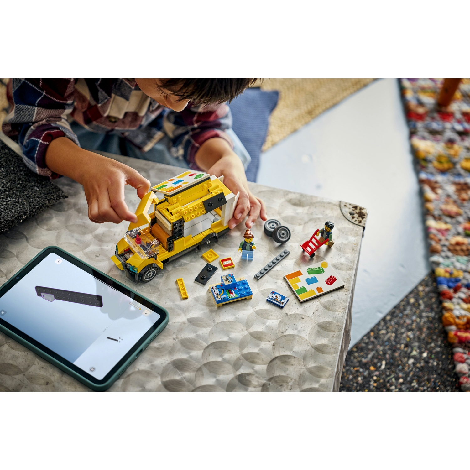Un bambino gioca con i Lego. Un autobus Lego giallo è su un tavolo con altri pezzi Lego e un tablet con le istruzioni.