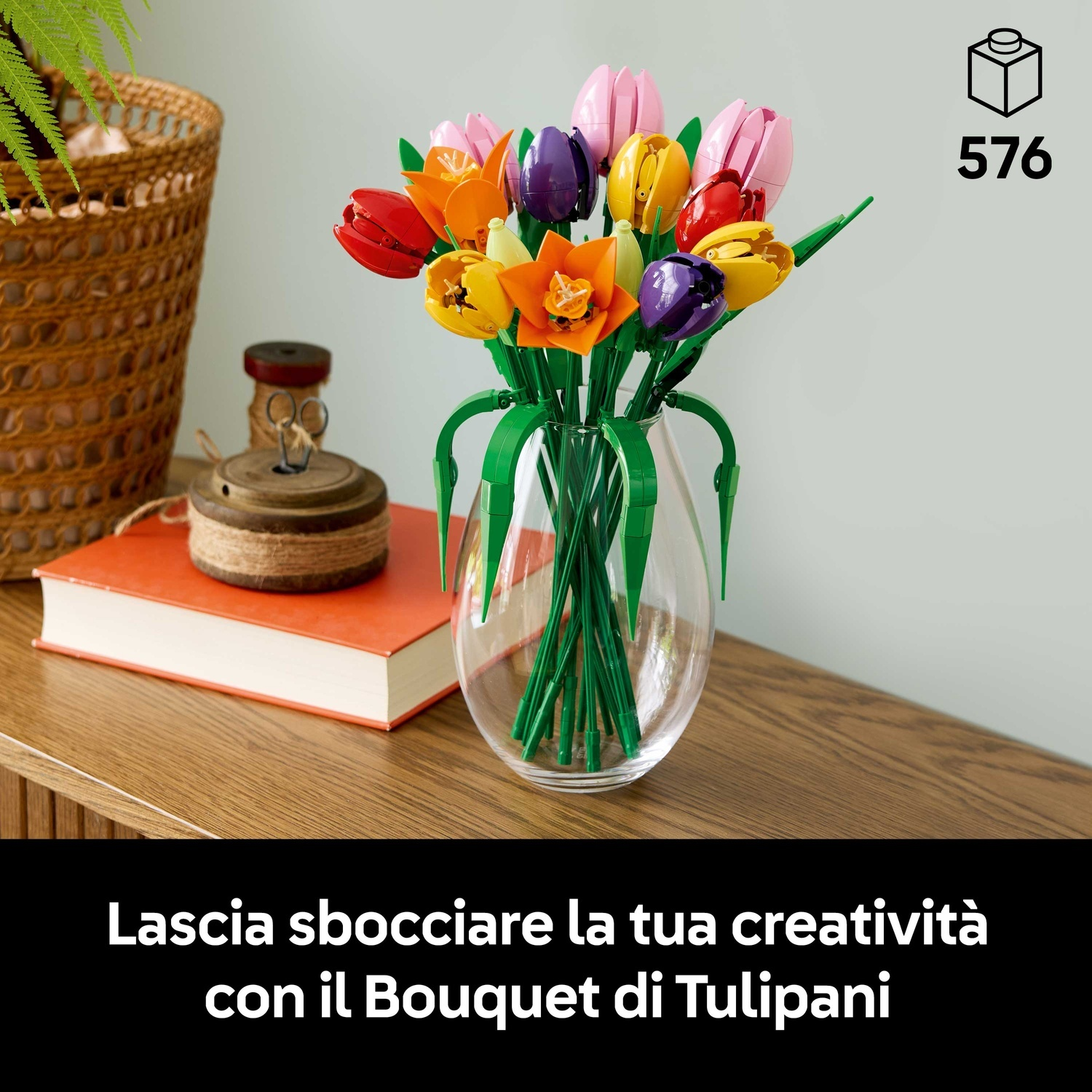 Un mazzo di tulipani Lego colorati in un vaso trasparente. I tulipani sono di vari colori. Il vaso è su un tavolo di legno.