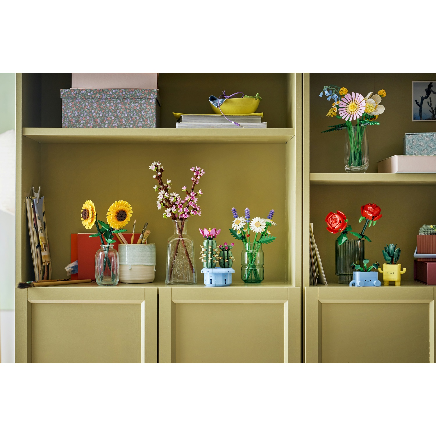 Scaffali con fiori Lego in vasi. Girasoli, margherite, rose e cactus sono esposti, insieme ad altri oggetti decorativi.